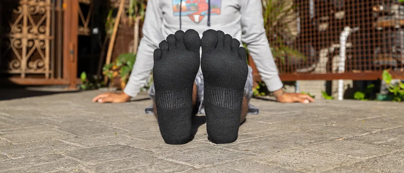 Woman sitting and showing off her black toe socks for hiking